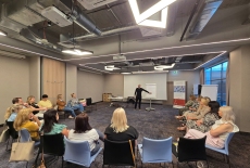 Uczestnicy siedzą na krzesłach i dyskutują.