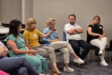 Uczestnicy siedzą na krzesłach i dyskutują.