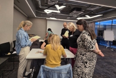 Uczestnicy siedzą przy stole i układają patyczki.