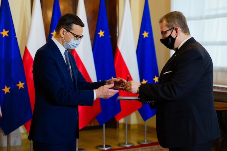 Fot: Krystian Maj/KPRM Wręczenie medalu, w tle polskie i unijne flagi